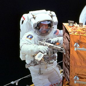 A space shuttle spacewalker with a drill specially fitted for space.